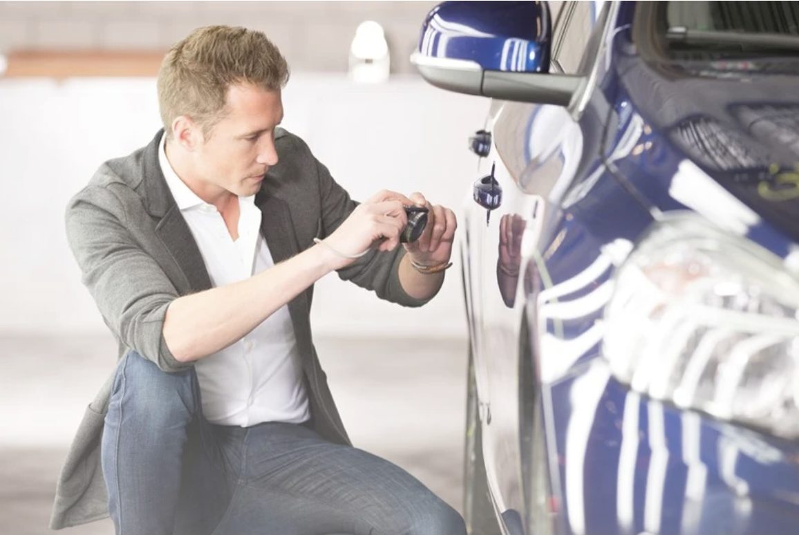 A team member inspecting and photographing a vehicle on handover